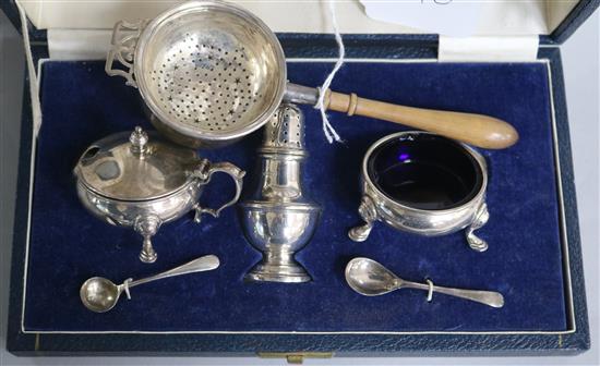 A 1950s cased silver three piece condiment set and a silver tea strainer with stand.